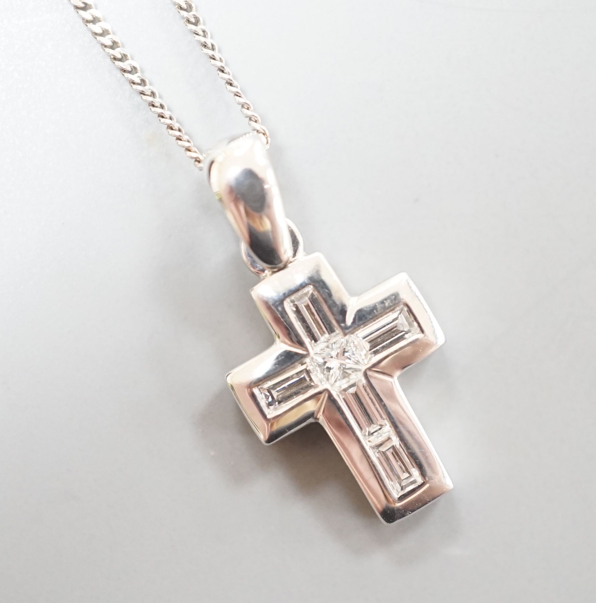 A modern 18ct white gold, baguette and princess cut diamond set cross pendant, 14mm, on an 18ct white gold fine link chain, 46cm, gross 3.8 grams